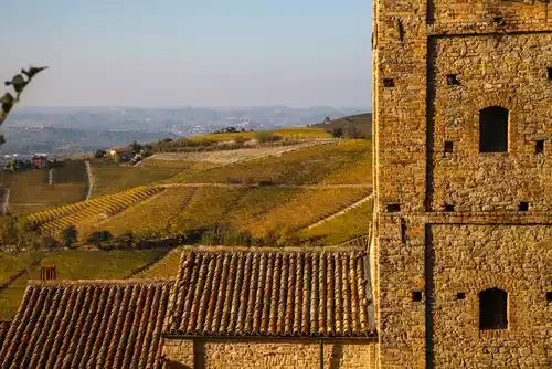 A stone building and hills of vines behind in 2020 Barolo