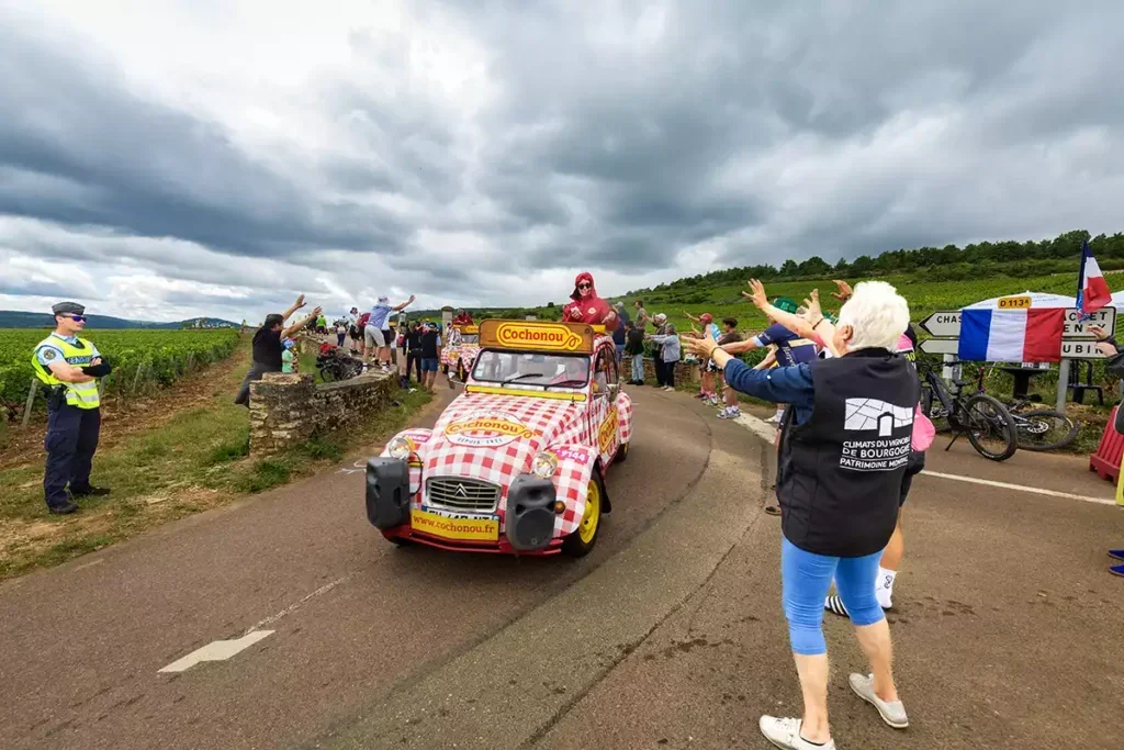 A Citroën 2CV decorated in red-and-white check and branded with the red-on-yellow Cochonou logo of the Tour de France sponsor, sausage maker, Cochonou 